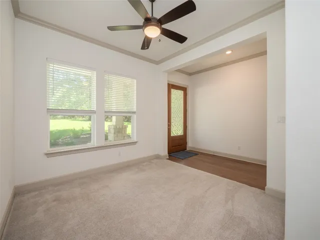 an empty room with chandelier fan and windows