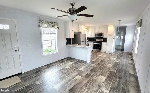a living room with stainless steel appliances kitchen island hardwood floor and a window