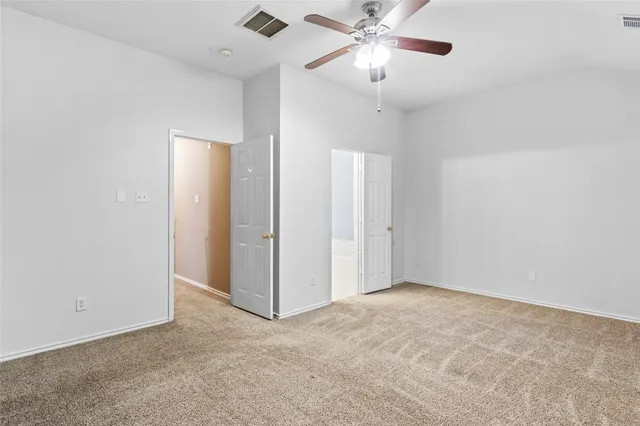 an empty room with a chandelier fan and closet area