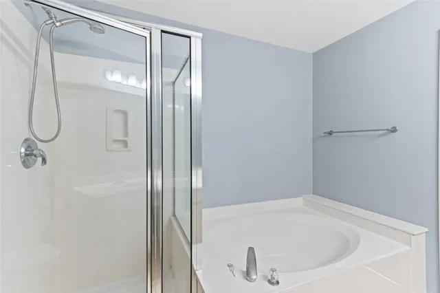a bathroom with a white bath tub sitting next to a shower