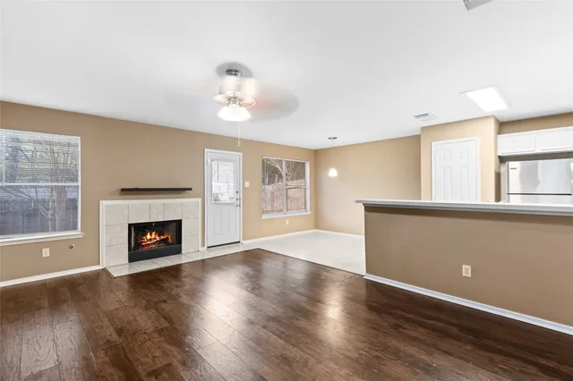 an empty room with windows fireplace and wooden floor