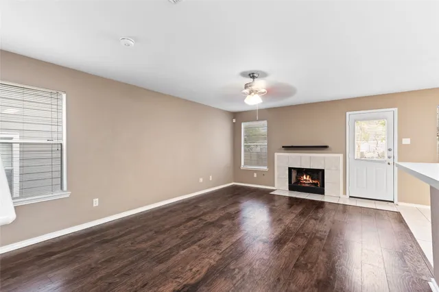 a view of an empty room with wooden floor fireplace and a window