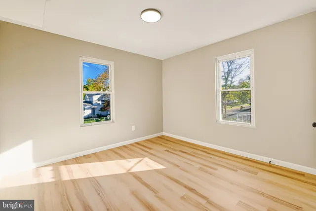 a view of an empty room with window and wooden floor