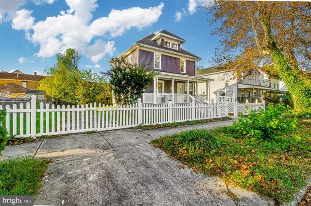 a view of a house with a small yard and wooden fence