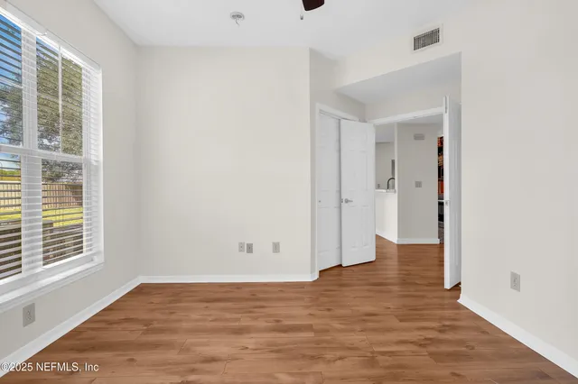 a view of an empty room with wooden floor and a window