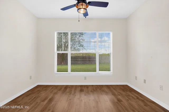 an empty room with wooden floor cabinet and windows