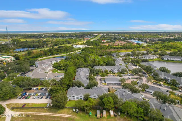 an aerial view of ocean and residential houses with outdoor space and swimming pool
