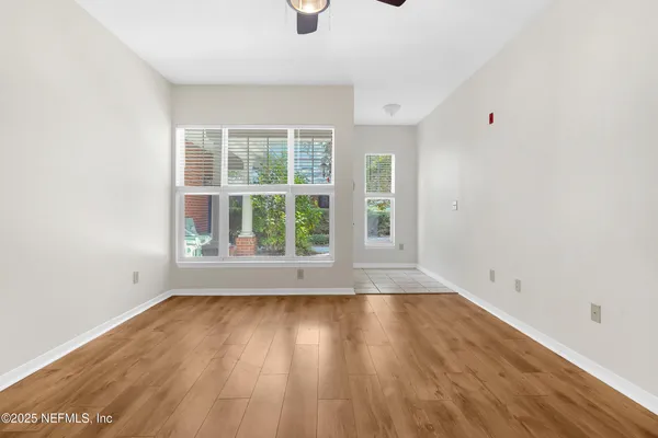 an empty room with wooden floor and windows