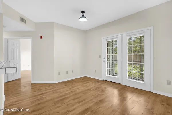 an empty room with wooden floor and windows