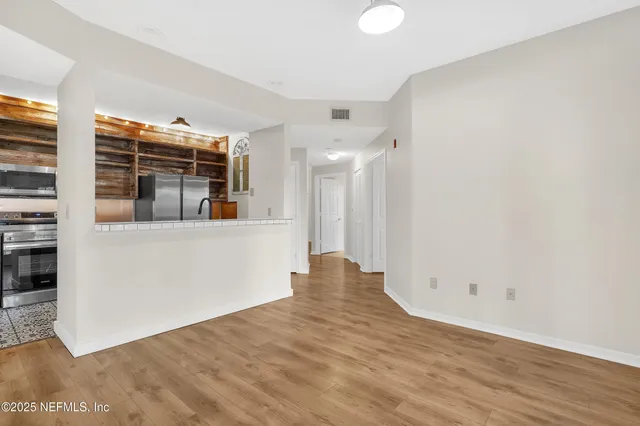 a view of empty room with wooden floor and fan