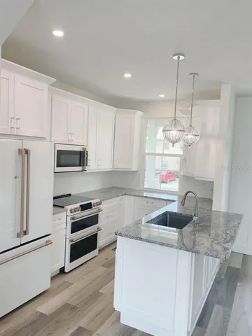 a kitchen with granite countertop a sink cabinets and stainless steel appliances