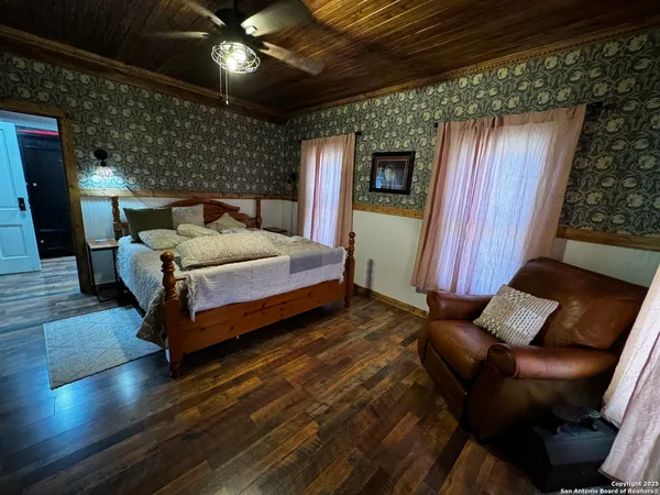 a spacious bedroom with a bed and wooden floor