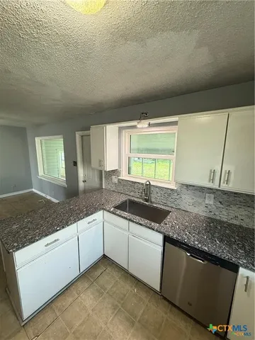 a kitchen with granite countertop a sink and a white cabinets
