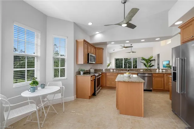 a kitchen with a refrigerator a sink dishwasher a dining table and chairs with wooden floor