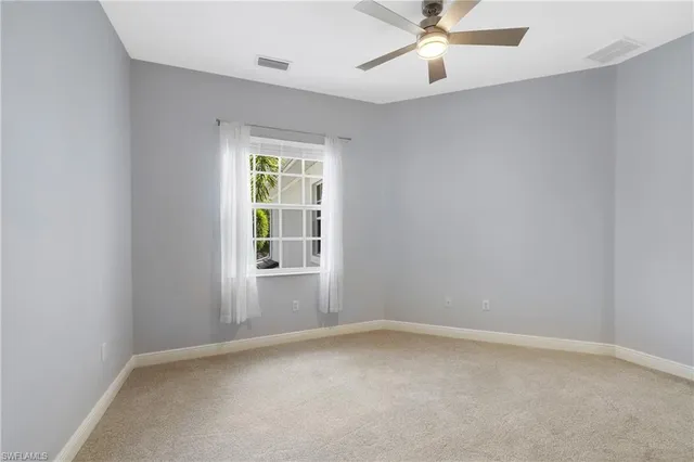 an empty room with a window and a fan