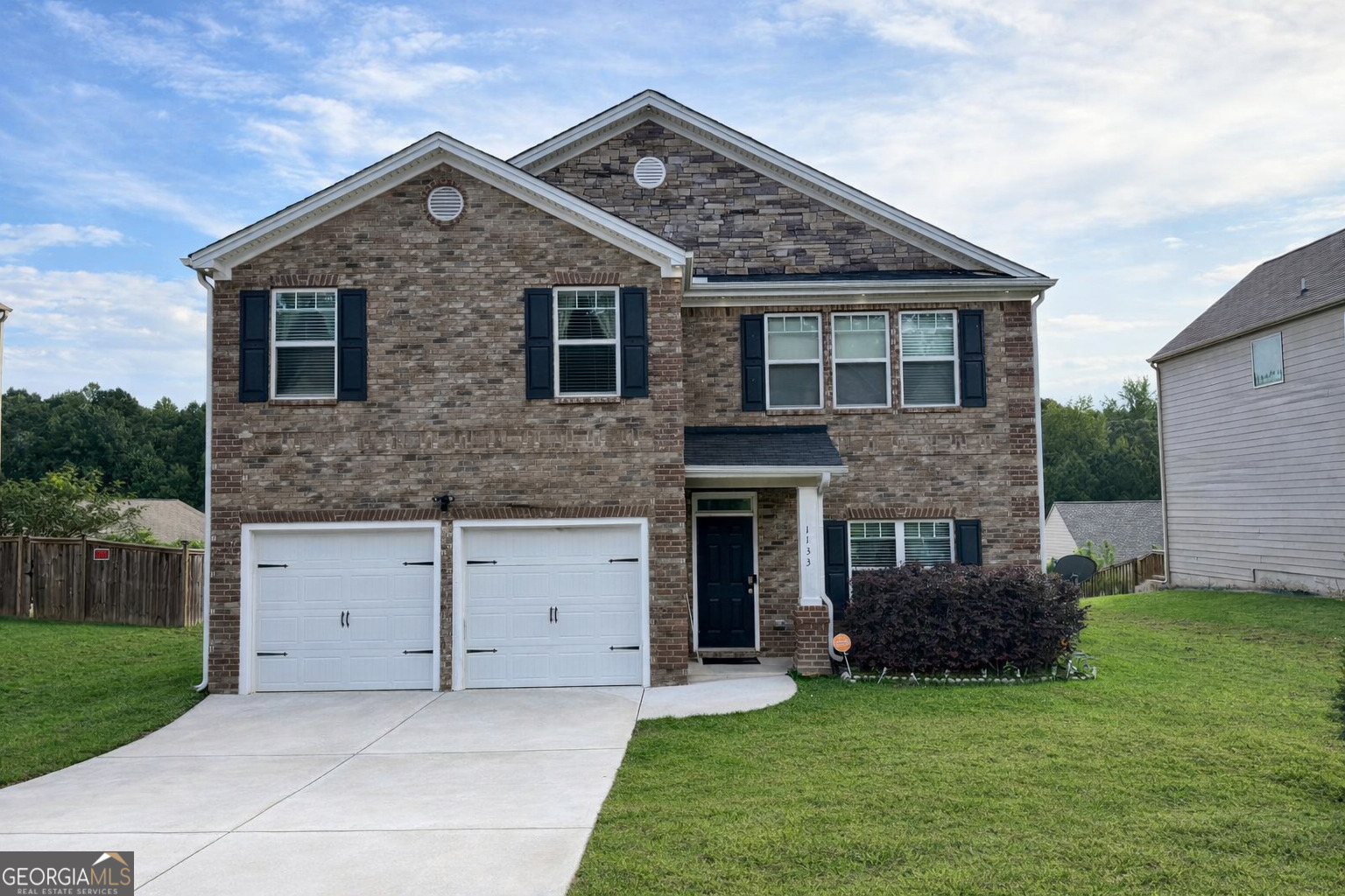 a front view of a house with a garden and yard