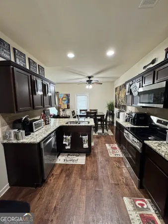 a kitchen with stainless steel appliances kitchen island granite countertop a stove refrigerator and a microwave