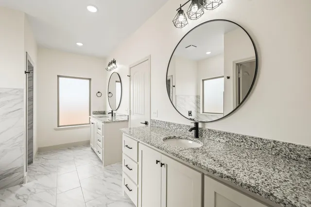 a spacious bathroom with a granite countertop sink a mirror and a shower
