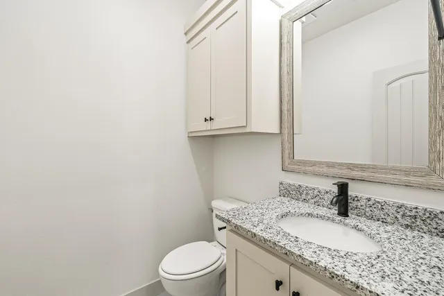 a bathroom with a granite countertop toilet sink and mirror