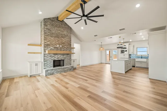 a view of empty room with wooden floor and a fireplace