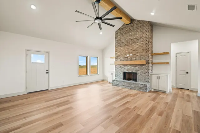 an empty room with wooden floor a fireplace and a window