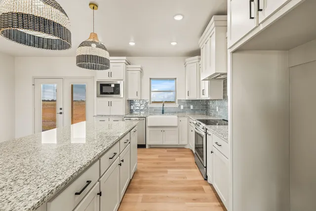 a large kitchen with granite countertop a large center island a sink stainless steel appliances and cabinets