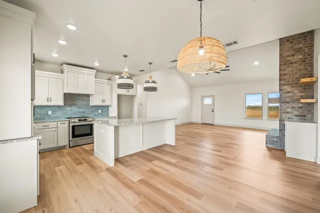 a large kitchen with granite countertop a stove and cabinets