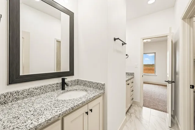 a bathroom with a granite countertop sink and a toilet