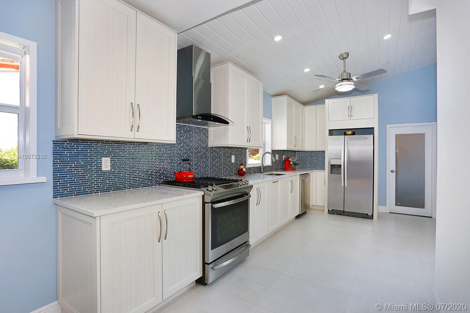 5161 Alton Road Miami Beach, FL 33140 - Photo 11 of 25 a kitchen that has a lot of white cabinets and stainless steel appliances