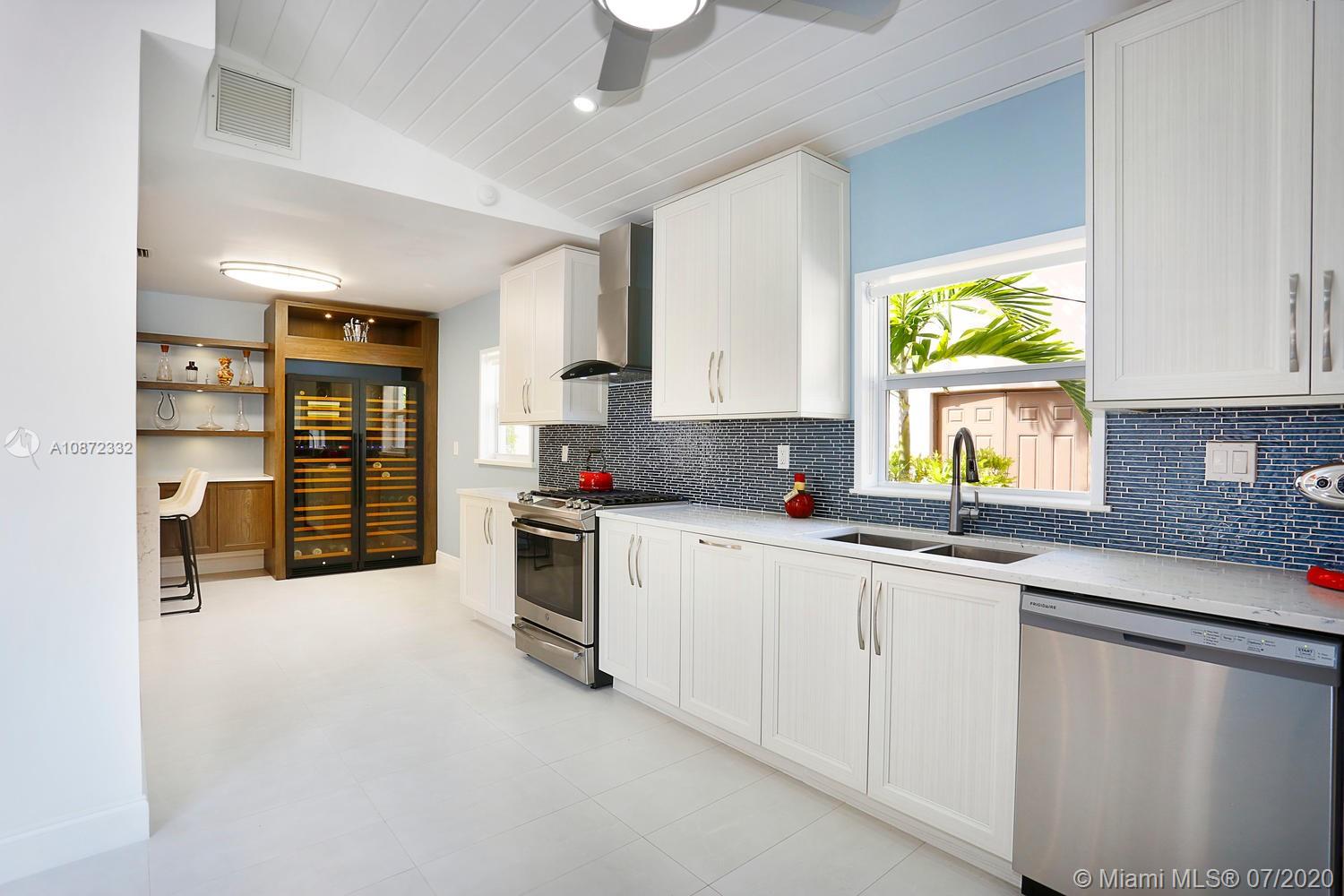 5161 Alton Road Miami Beach, FL 33140 - Photo 10 of 25 a kitchen with stainless steel appliances granite countertop a stove a sink and a granite counter tops with white cabinets