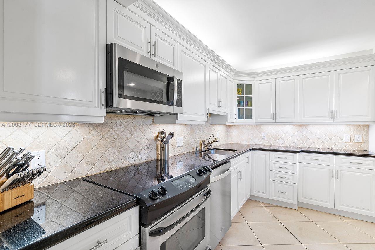 400 Ocean Trail Way, Unit 302 Jupiter, FL 33477 - Photo 3 of 29 a kitchen with granite countertop white cabinets and appliances