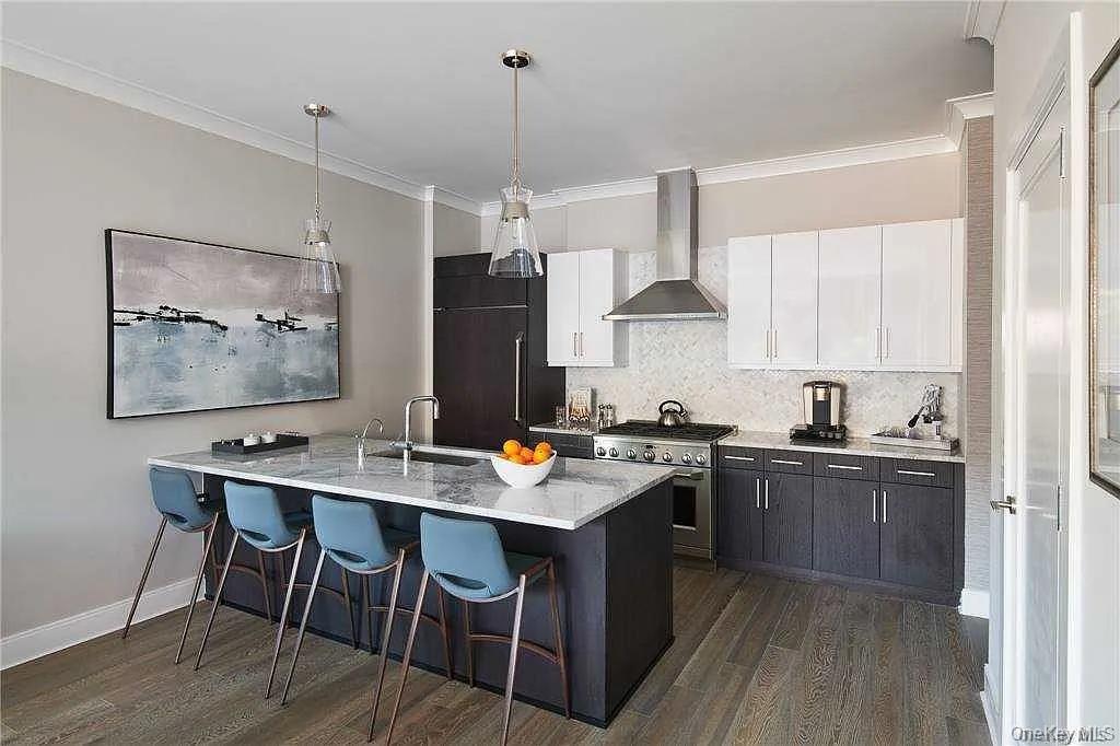 100 Garvies Point Road, Unit 1146 Glen Cove, NY 11542 - Photo 4 of 11 a kitchen with stainless steel appliances granite countertop a stove a refrigerator a sink a dining table and chairs with wooden floor