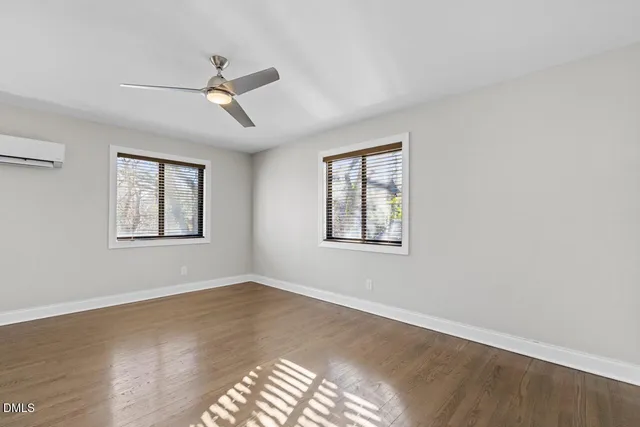 an empty room with wooden floor fan and windows