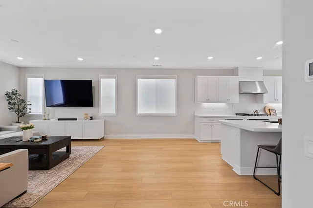 a kitchen that has a sink a stove a refrigerator and white cabinets with wooden floor