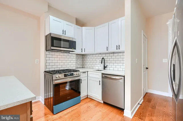 a kitchen with cabinets stainless steel appliances and wooden floor