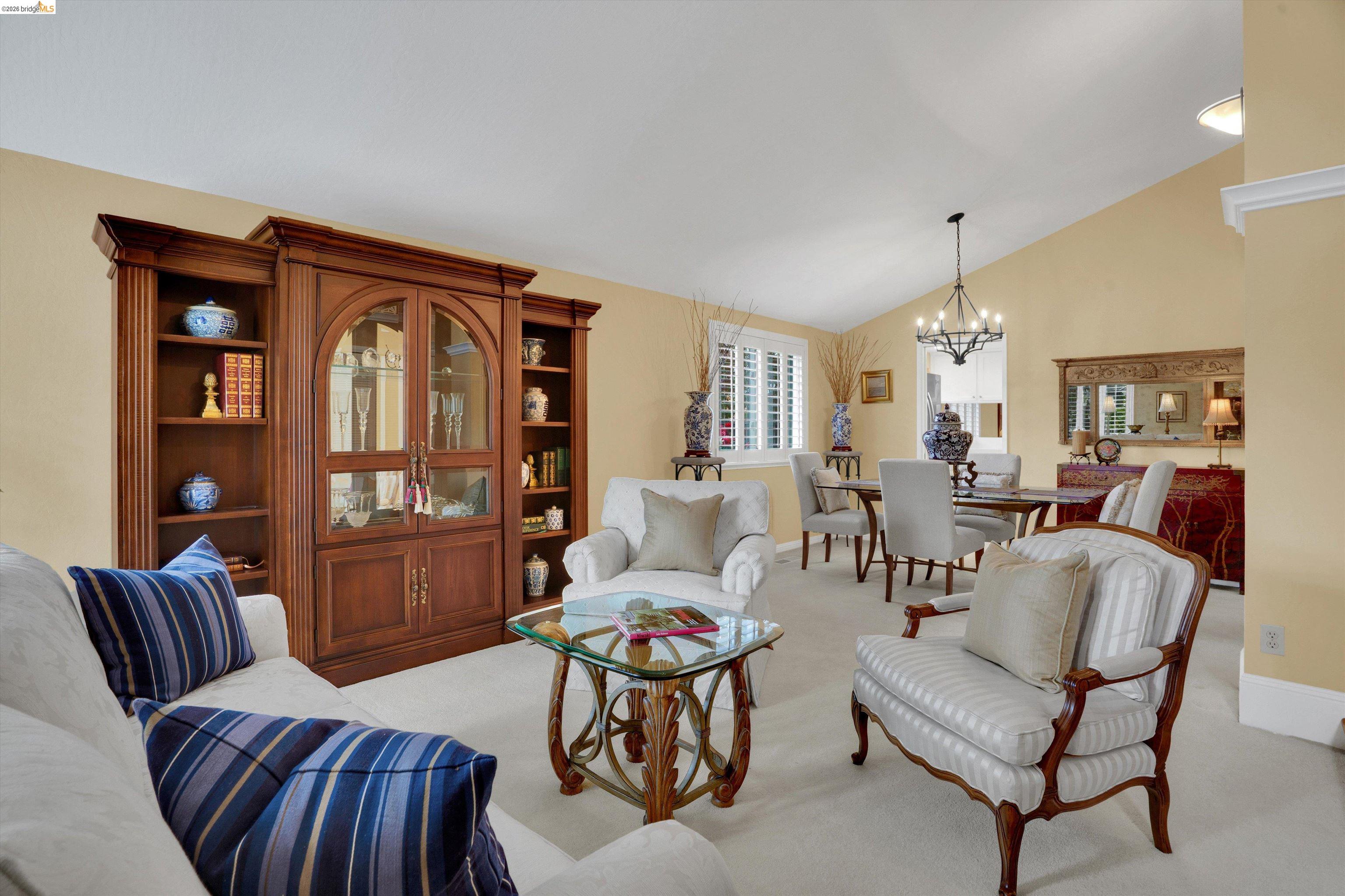5001 St Garrett Court Concord, CA 94521 - Photo 14 of 45 Vaulted ceiling living space featuring a built-in wood-finish display cabinet, plush carpeting, and a dining area with a chandelier