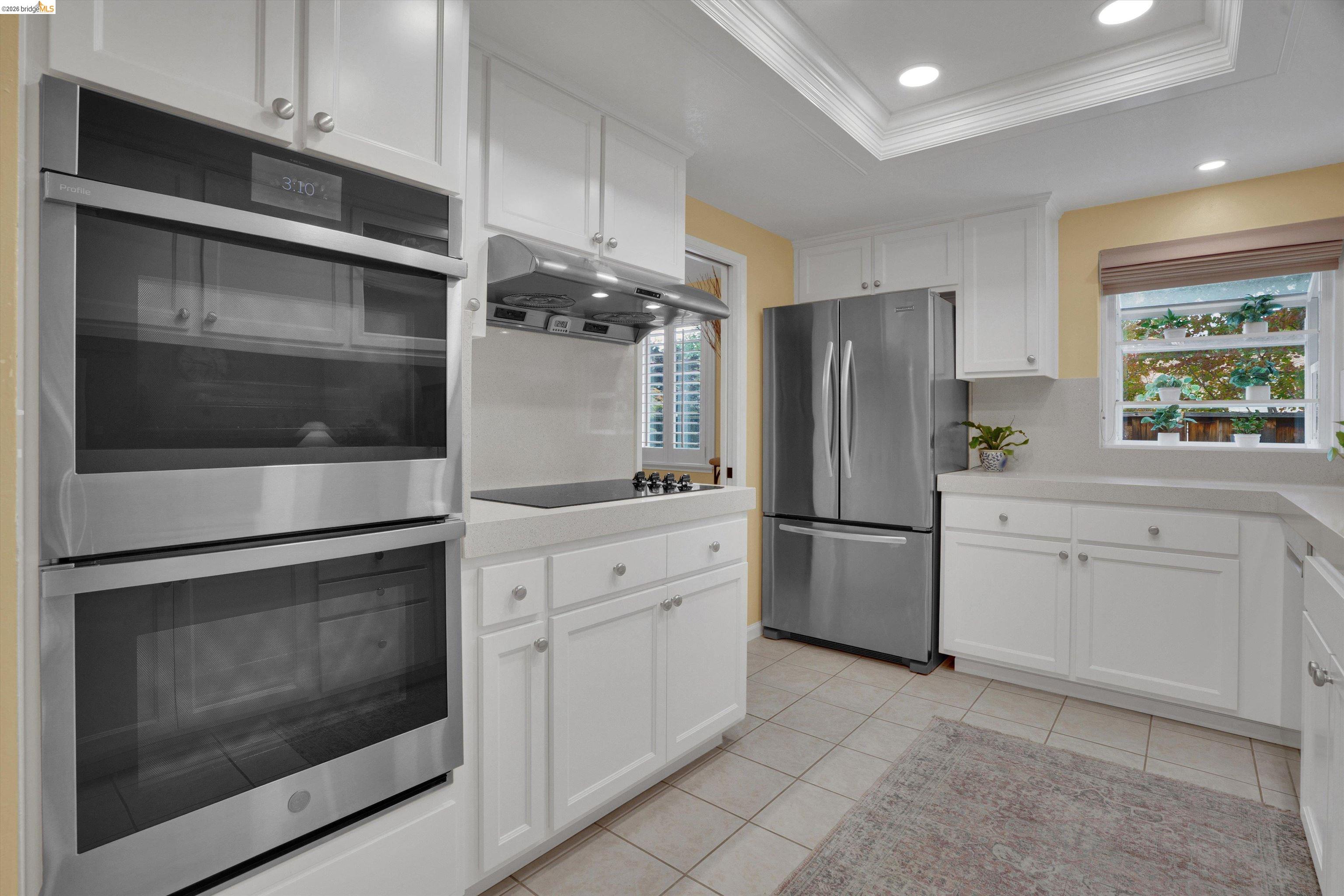 5001 St Garrett Court Concord, CA 94521 - Photo 22 of 45 Kitchen featuring a double wall oven, stainless steel refrigerator, white cabinetry with silver hardware, an electric cooktop with range hood, and tile flooring