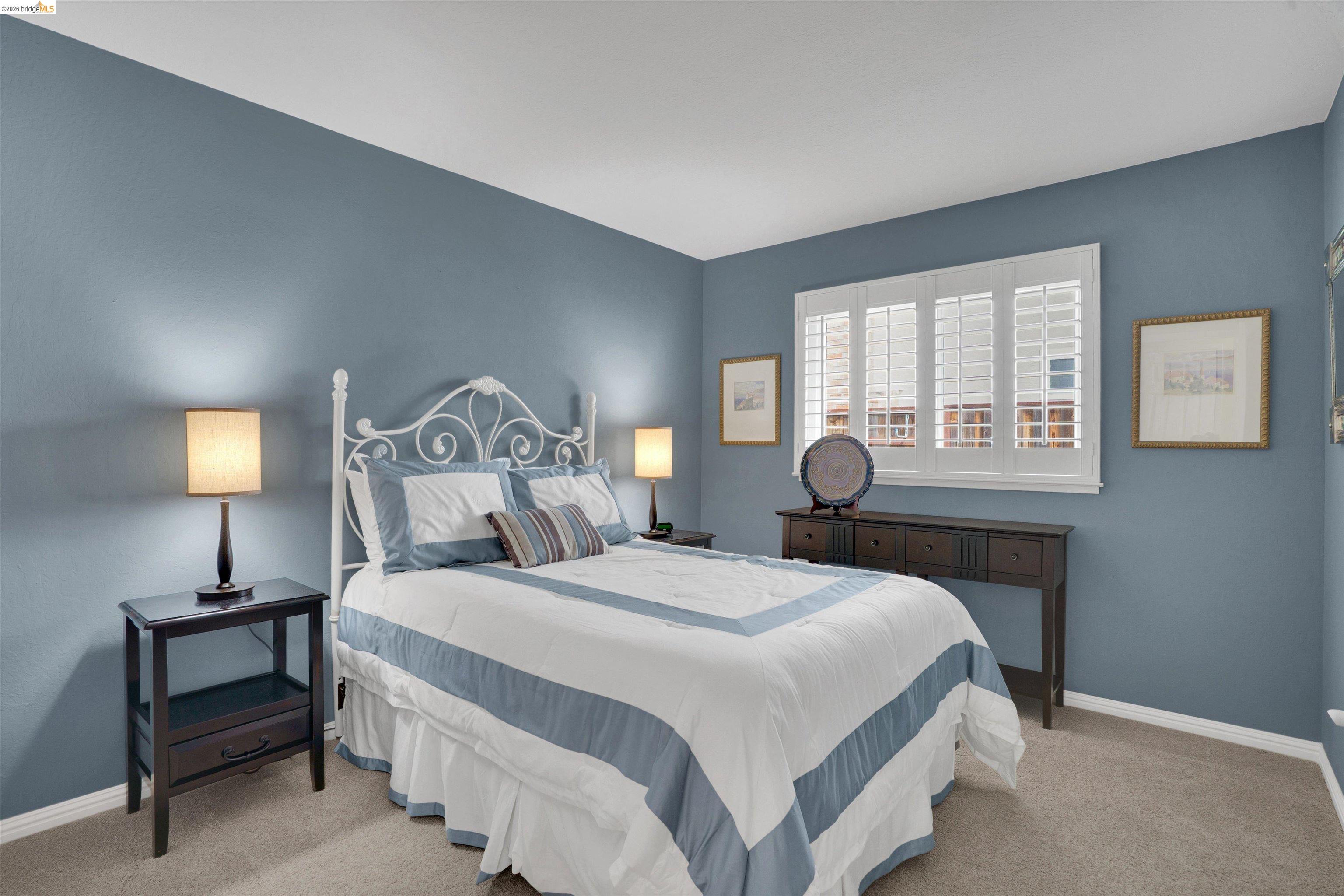 5001 St Garrett Court Concord, CA 94521 - Photo 30 of 45 Spacious bedroom featuring neutral carpeting, light blue wall paint, a large window with white plantation shutters, and white baseboards