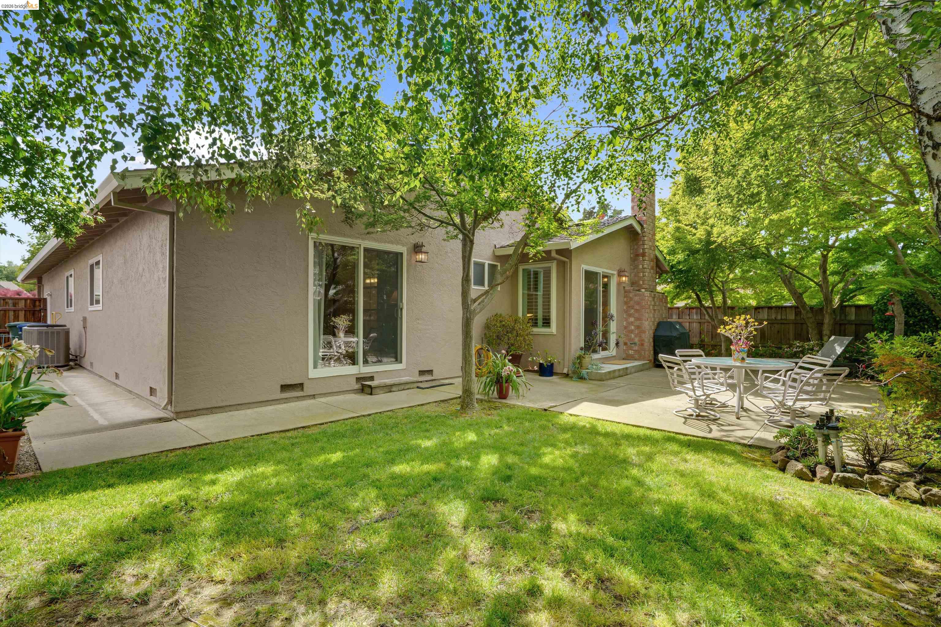 5001 St Garrett Court Concord, CA 94521 - Photo 37 of 45 Manicured backyard featuring a concrete patio, mature trees, and a stucco exterior with sliding glass doors