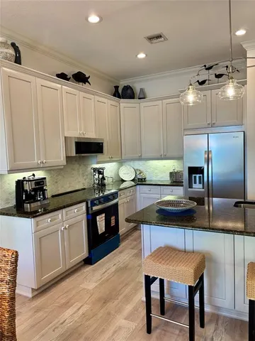 a kitchen with kitchen island granite countertop a sink cabinets and stainless steel appliances