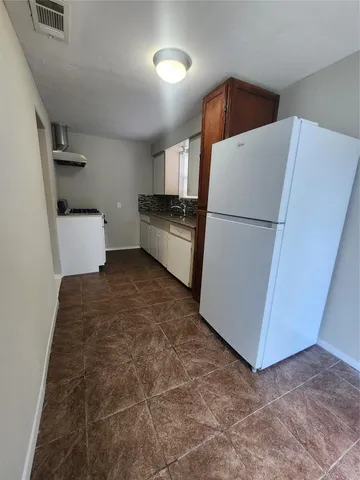 a kitchen with a refrigerator and white cabinets