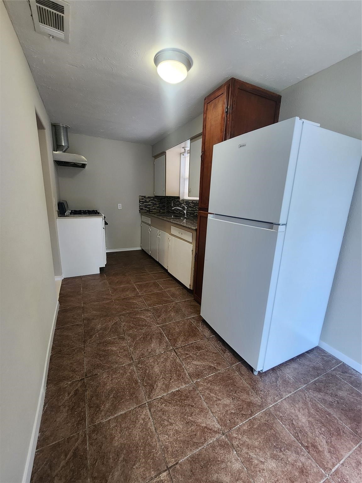 221 East Lobit Avenue, Unit A Baytown, TX 77520 - Photo 2 of 6 a kitchen with a refrigerator and white cabinets