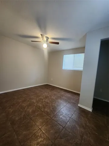 an empty room with wooden floor fan and window