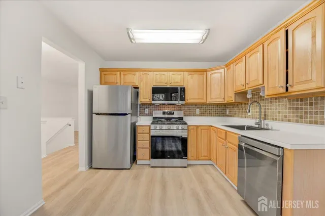 a kitchen with stainless steel appliances granite countertop a stove top oven a sink and a refrigerator