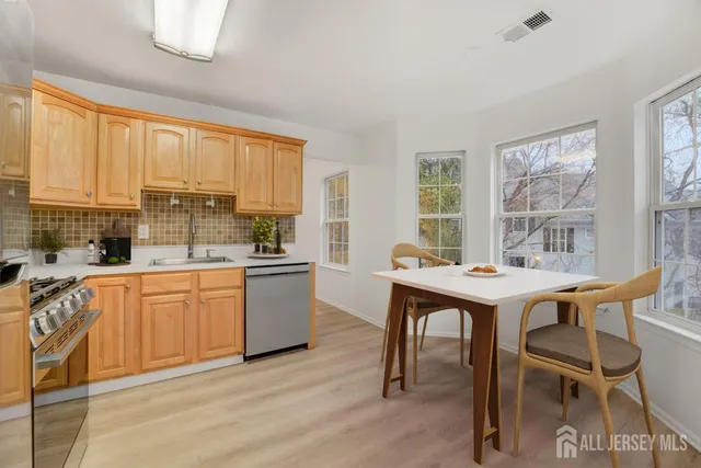 a kitchen with stainless steel appliances granite countertop a table chairs sink and cabinets
