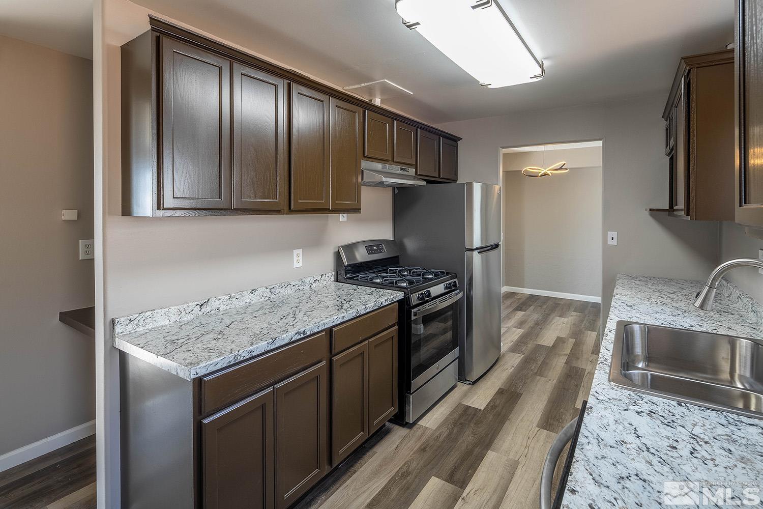 16310 Enargite Circle Reno, NV 89521 - Photo 5 of 32 a kitchen with granite countertop stainless steel appliances a sink stove refrigerator and cabinets