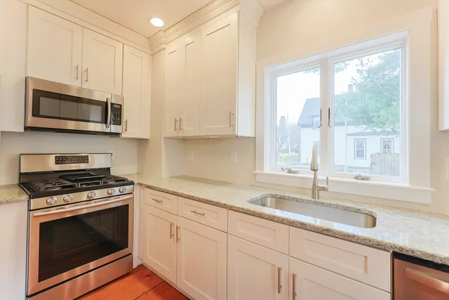 a kitchen with granite countertop white cabinets and white appliances