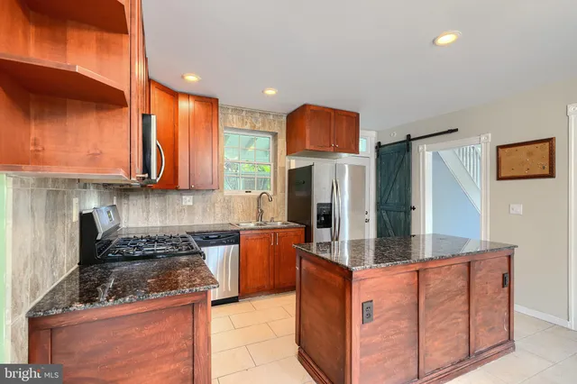 a kitchen with stainless steel appliances granite countertop a stove a sink and a refrigerator