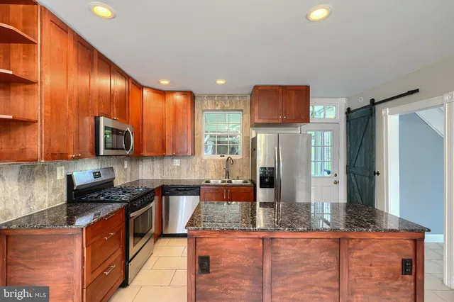 a kitchen with stainless steel appliances granite countertop wooden cabinets a stove top oven a sink and dishwasher