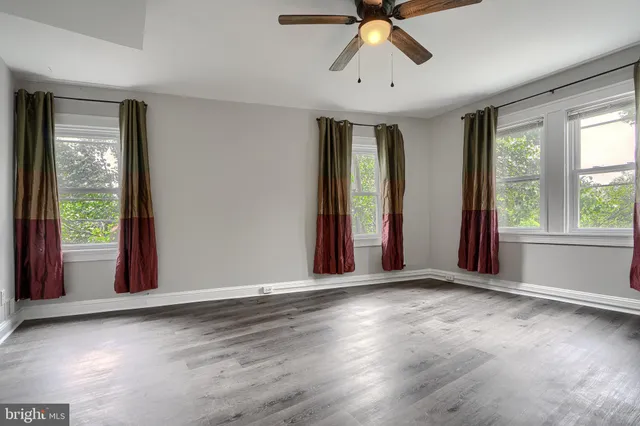 a view of an empty room with window and hardwood floor
